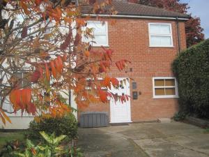 una casa de ladrillo con una puerta blanca y un árbol en Spacious Annexe in central Colchester, en Lexden