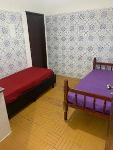 ein Schlafzimmer mit zwei Betten mit lila und violetter Bettwäsche in der Unterkunft Lar do Litoral - Praia Grande in Praia Grande