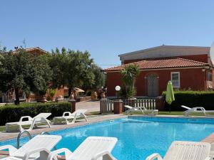 a swimming pool with white lounge chairs next to a house at Agriturismo Galeazzi in Marsiliana