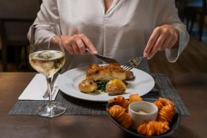 a person eating a plate of food with a glass of wine at HF Tuela Porto in Porto +16 photos