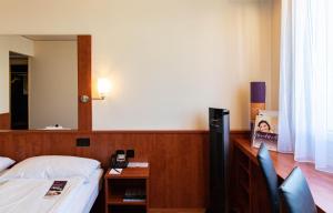 a bedroom with a bed and a desk with a telephone at Hotel Arte Spreitenbach in Spreitenbach