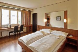 a bedroom with a large bed and a desk with chairs at Hotel Arte Spreitenbach in Spreitenbach +4 photos