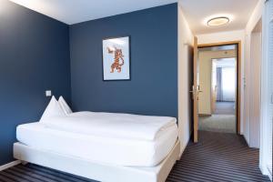 a bedroom with a large white bed in a blue wall at Self Check-In Hotel David 22 in St. Gallen