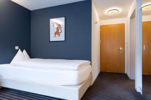 um quarto com uma grande cama branca com uma parede azul em Self Check-In Hotel David 22 em St. Gallen