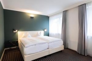 um quarto com uma grande cama branca e uma janela em Self Check-In Hotel David 22 em St. Gallen