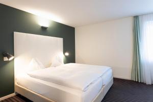um quarto com uma grande cama branca em um quarto em Self Check-In Hotel David 22 em St. Gallen mais 6 fotografias