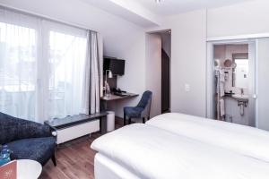 a hotel room with a bed and a desk and a window at Sorell Hotel Rex Zürich in Zürich