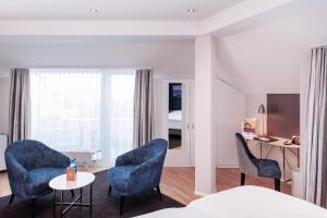 a bedroom with blue chairs and a table and a bed at Sorell Hotel Rex Zürich in Zürich