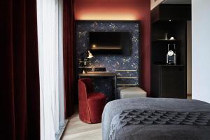 a bedroom with a red chair and a television at Sorell Boutique-Hotel Seefeld Zürich in Zürich