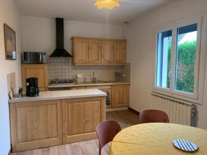 a kitchen with wooden cabinets and a table with chairs at L'Arbre de Vie in Montmarault +3 photos