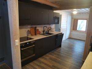a kitchen with black cabinets and a wooden floor at Villa Hackberry Hill in Rovaniemi