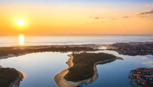 an island in the water with the sunset in the background at Notre bergerie in Soustons +7 photos