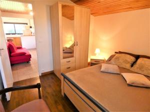 a bedroom with a large bed and a red chair at L'ecureuil in Soustons