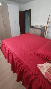 a red bed with a redspread on top of it at Omma's Haus - Casa de Vó perto de Gramado in Morro Reuter