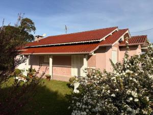 ein Haus mit rotem Dach und ein paar Blumen in der Unterkunft Omma's Haus - Casa de Vó perto de Gramado in Morro Reuter + 39 Fotos