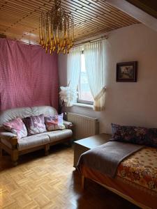 a bedroom with a bed and a couch and a chandelier at Ferienwohnung Jägerhaus in Walldürn