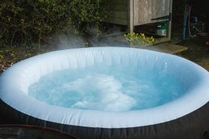 a hot tub filled with blue water in a backyard at Shepherds hut in Kent +1 photo