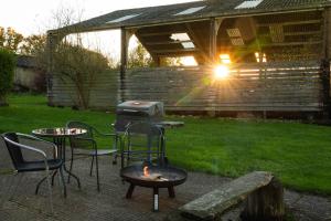 a fire pit in a backyard with chairs and a grill at Shepherds hut in Kent
