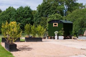 a green shed with a tree in a yard at Shepherds hut in Kent