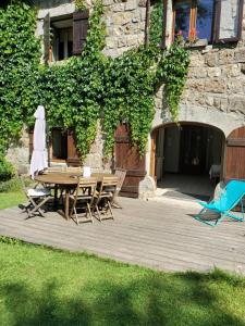 eine Holzterrasse mit einem Tisch und Stühlen vor einem Gebäude in der Unterkunft GITE LES MYOSOTIS in Le Chambon-sur-Lignon