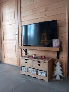 a entertainment center with a television on a wooden wall at Gîtes les COMBES in Saint-Léger-les-Mélèzes