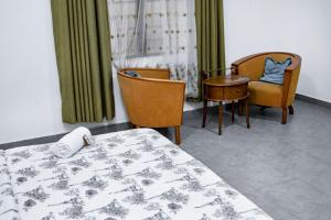 a room with a bed and two chairs and a table at Kwanskrom Villa Biggies Homes in Winneba +33 photos