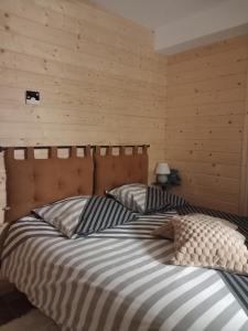 two beds in a bedroom with wooden walls at Gîtes les COMBES in Saint-Léger-les-Mélèzes