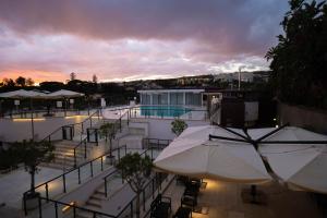 カターニアにある4 スパ リゾート ホテルのパラソルとプールのある建物の眺め