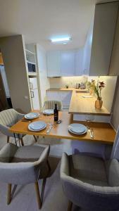 a kitchen with a wooden table with plates and chairs at Beachfront Premium Apartment with Sunset, Pools & Sea View in Portimão