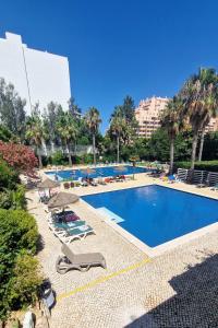 a swimming pool with chaise lounge chairs and a resort at Beachfront Premium Apartment with Sunset, Pools & Sea View in Portimão