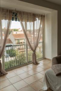 ein Schlafzimmer mit großem Fenster und Balkon in der Unterkunft Grand appartement 2 chambres avec wifi in Perpignan