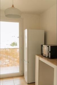 eine Küche mit Kühlschrank und Mikrowelle in der Unterkunft Grand appartement 2 chambres avec wifi in Perpignan