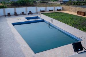 a large swimming pool with blue water at Kwanskrom Villa Biggies Homes in Winneba