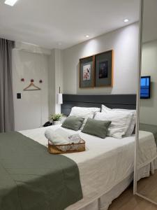 ein Schlafzimmer mit einem großen Bett mit weißen Laken und Kissen in der Unterkunft Conecta Flats - De frente para Pedra Azul in Pedra Azul