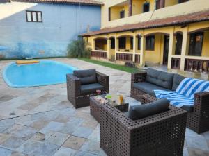a patio with wicker furniture and a swimming pool at Villa Mediterraneo in Beberibe
