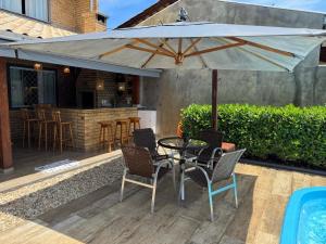 eine Terrasse mit Tisch, Stühlen und Sonnenschirm in der Unterkunft Refúgio Rustico em Penha in Penha