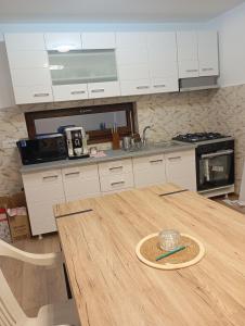 une cuisine avec une table en bois et des armoires blanches dans l'établissement Mircea, à Craiova