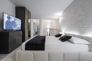 a bedroom with a large bed and a flat screen tv at Gramsci Prestige Apartment in Bologna