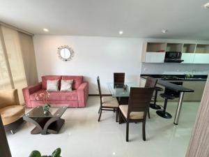 a living room with a pink couch and a glass table at Club house 1105-Apartamento Fundadores con balcón, piscina, gym in Armenia
