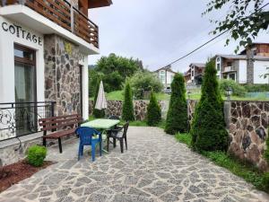 une terrasse avec un banc, une table et des chaises dans l'établissement Cottage Sunny Side, à Bakuriani