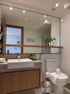 ein Badezimmer mit Waschbecken, Toilette und Spiegel in der Unterkunft Conecta Flats - De frente para Pedra Azul in Pedra Azul