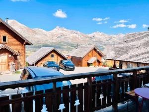 un balcon avec des voitures garées devant certains bâtiments dans l'établissement Chalet la montagne numero 10, à La Joue du Loup