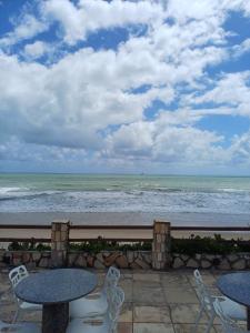 eine Terrasse mit Tischen und Stühlen und Meerblick in der Unterkunft Villa Búzios in Nísia Floresta
