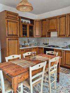 eine Küche mit einem Holztisch und weißen Stühlen in der Unterkunft Appartamento in struttura indipendente Appartamenti di Mezzo in Cecino