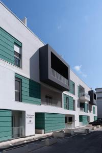 a building with green and white windows and a parking lot at Dimore Rosselli Suites in Fasano