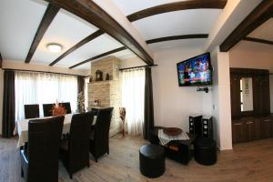 une salle à manger avec une table et une télévision au plafond dans l'établissement Vila Romanita, à Păltiniş