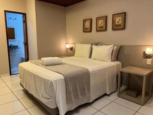 um quarto com uma cama grande com lençóis brancos em Pousada Canto do Sabiá - Pirenópolis em Pirenópolis mais 38 fotografias