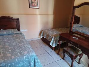 Zimmer mit 2 Betten, einem Tisch und einem Spiegel in der Unterkunft Hotel Real De Cortes in Xalapa