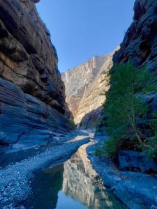 a river in the middle of a canyon at إطلالة غروب الشمس in Misfāh +13 photos