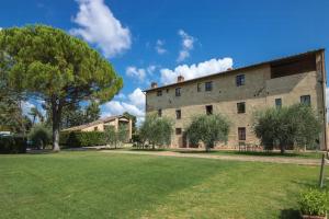 un grand bâtiment en pierre avec une cour verte dans l'établissement Historic Farmhouse Overlooking San Gimignano, à San Gimignano